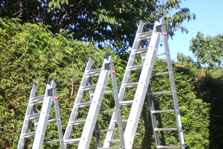 Drei Leitern mit verschiedener Länge vor Heckke 